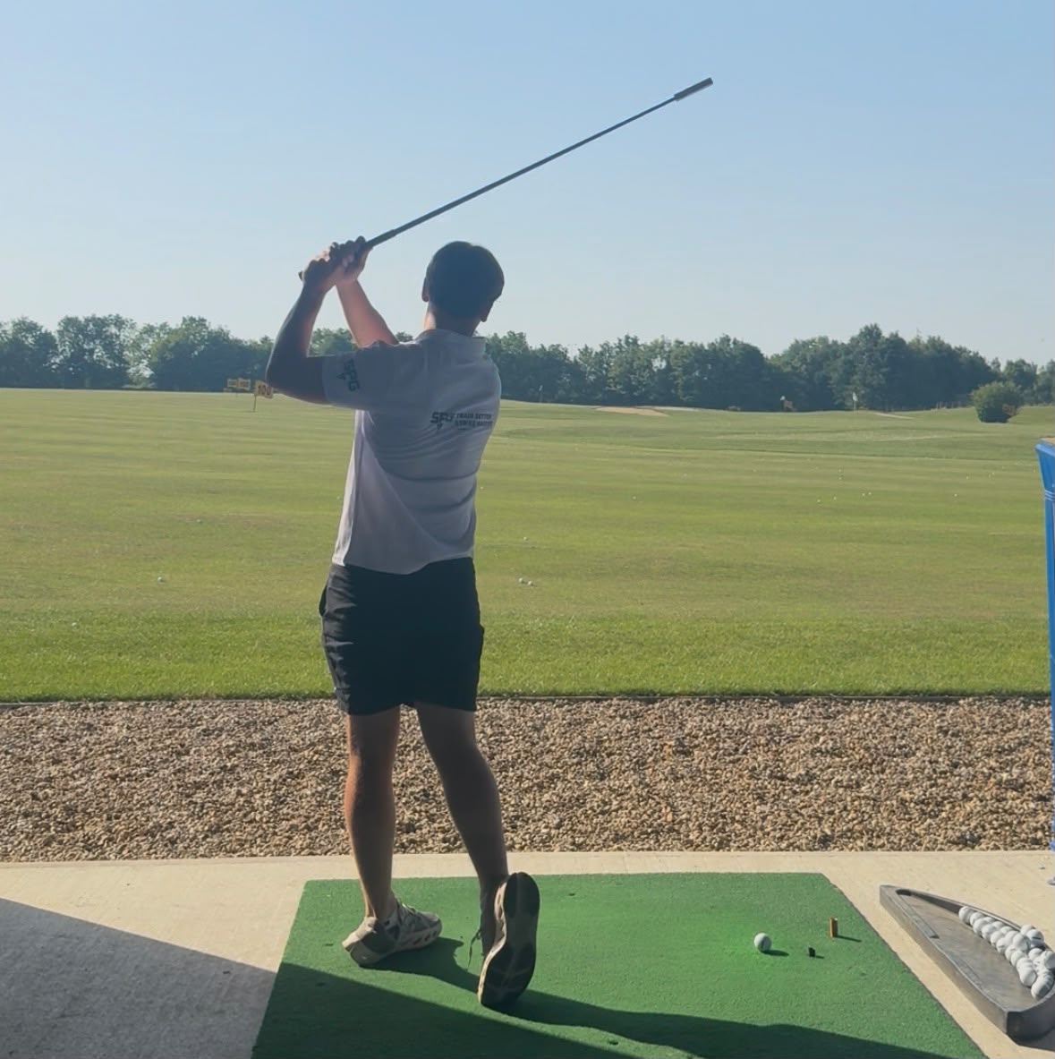 Golfer at full extension in the follow-through after a maximum-intent overspeed training swing